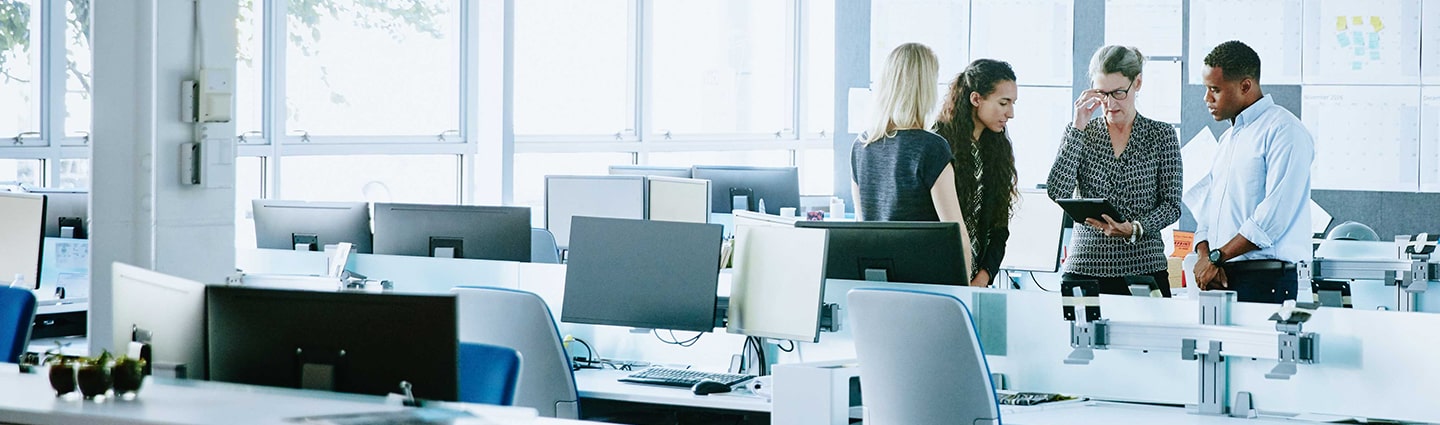 Ivalua Accessibility. 4 Coworkers congregating by a desk of an empty office